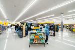 Giant Tiger Boisbriand, Que., featuring neatly arranged racks of apparel, hats, and accessories. A mannequin dressed in a blue hoodie stands near a display table showcasing colorful graphic t-shirts. Overhead signs direct shoppers to different sections...