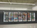 Giant Tiger Camrose, Alta., grocery aisle featuring refrigerated shelves stocked with various food items such as frozen and packaged foods. 