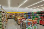 Giant Tiger Saint John, N.B., grocery aisles featuring shelves of chips and pop, with bins in the middle filled with an assortment of snacks, displayed in front of the word “Grocery” that is above the shelves of chips and salty snacks. 